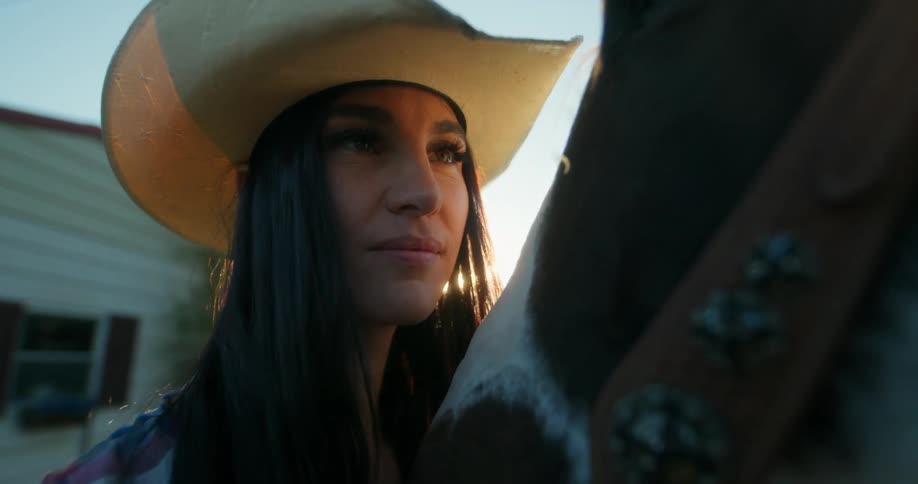 A woman kisses a horses nose then laughs
