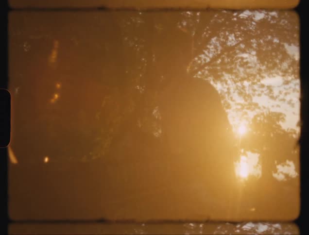 A man is lying down and then sits up and there is a bright sun in the background