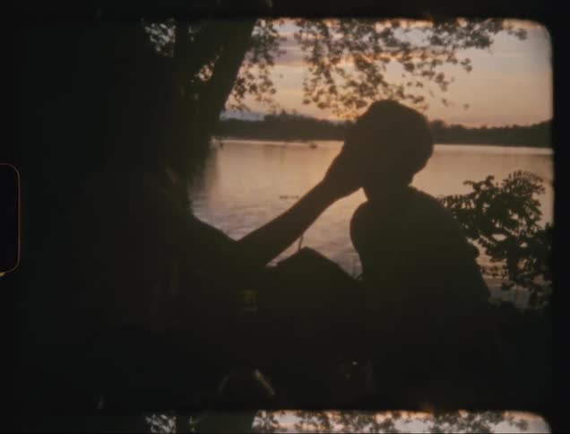 Man touches the face of a lady while on a picnic near a river during the day