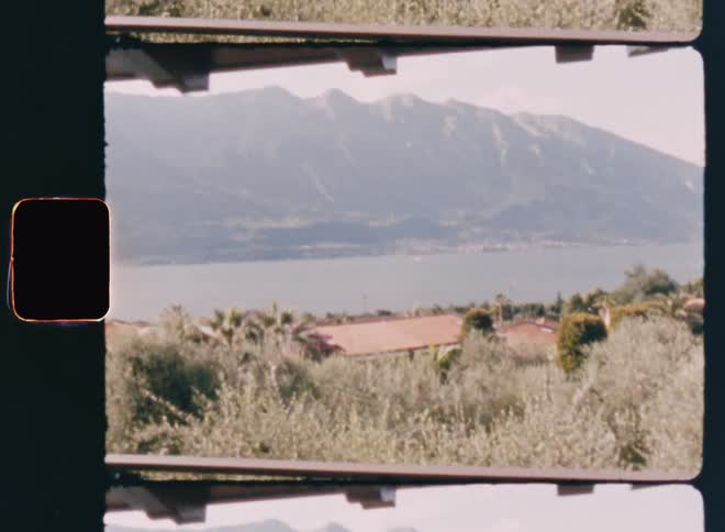 A window where the view overlooks a region with a lake and a huge mountain