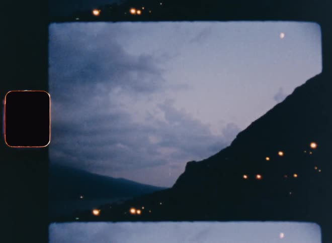 Lights dot the mountainside on a cloudy day at dusk