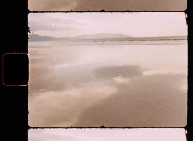 Waves lap the shore of a lakeside beach on a partly cloudy day