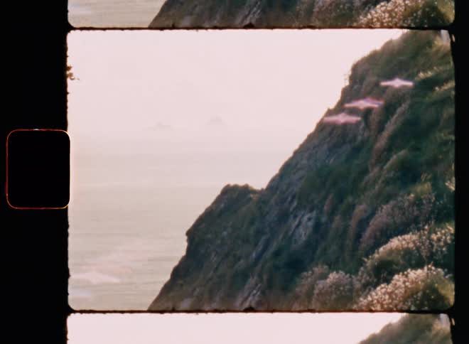 Top of a mountain with grass and the ocean in the background