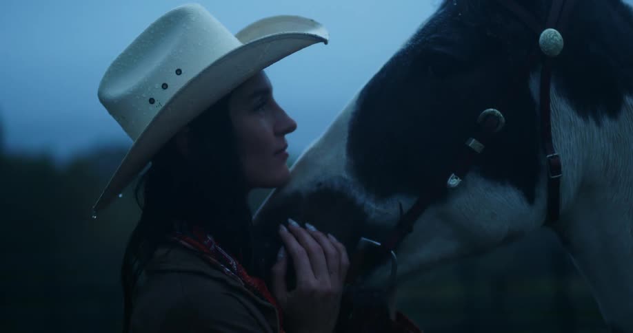 Rain falls onto woman stroking and kissing horses face