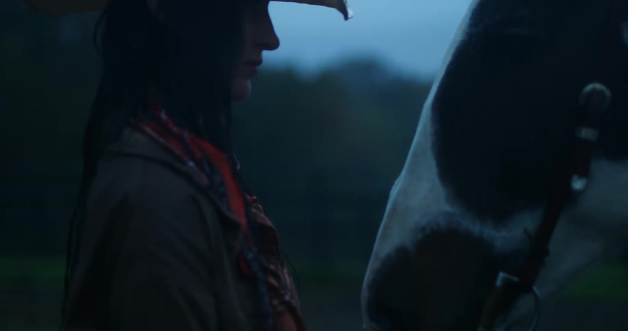 A lady standing under the rain beside her horse