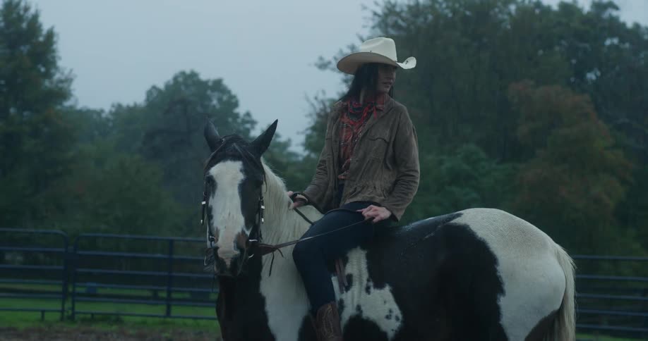 Cowgirl riding a horse in the rain