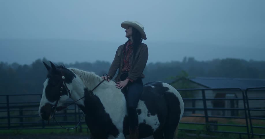 Cowgirl on horseback in the rain arms open