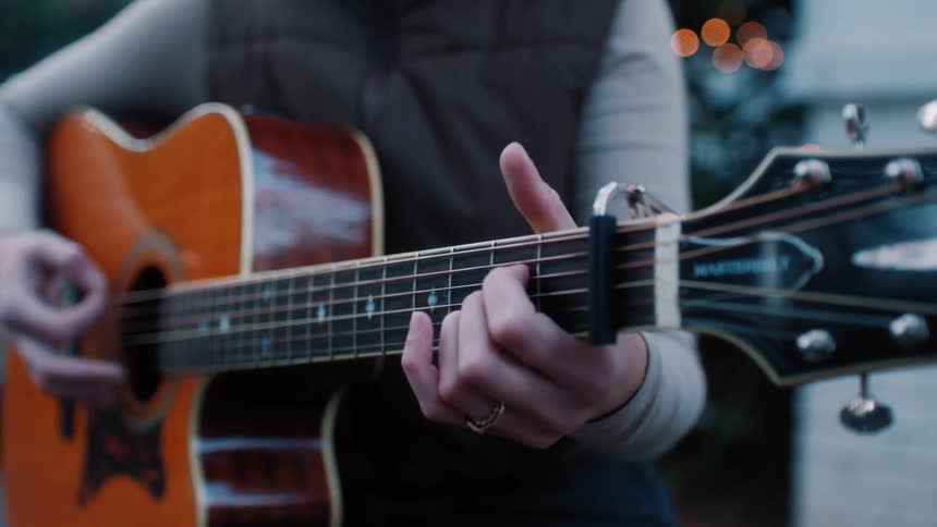 Female guitarist plays acoustic guitar outdoors