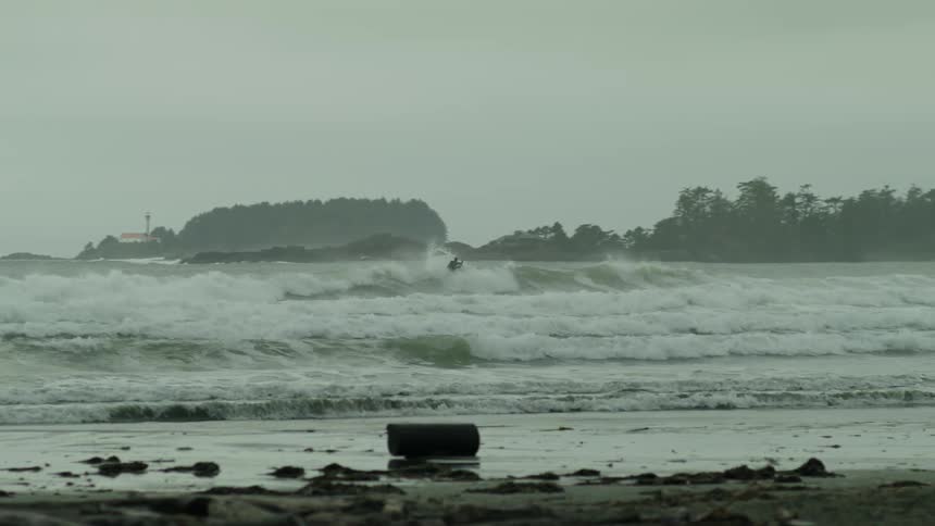 Person surfing a wave at the beach on a cloudy day
