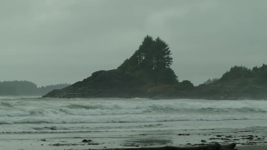 Ocean waves crash against the shoreline on a cloudy day