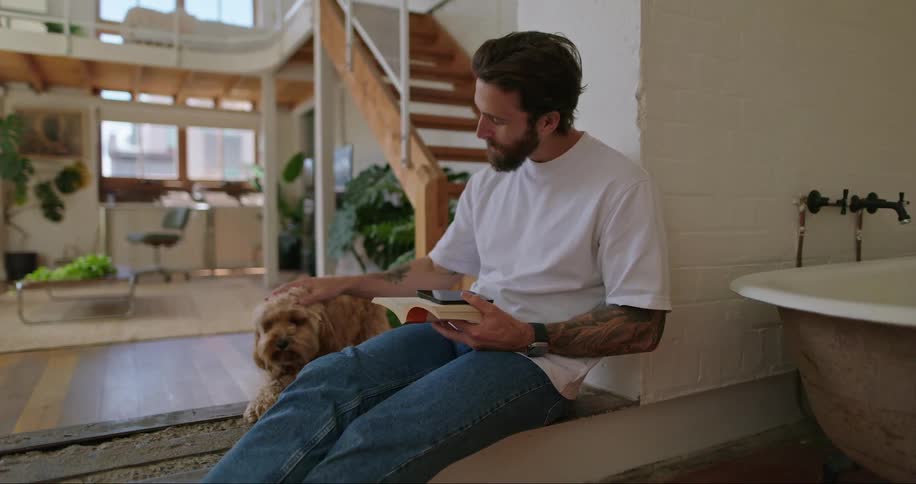 A man sitting on the floor of his house petting a dog