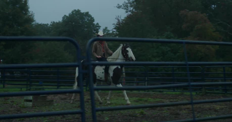 Woman riding a horse inside an enclosure in low light