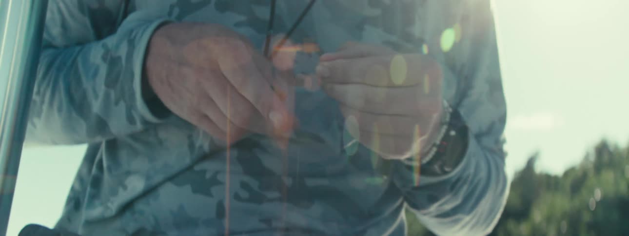 A man is putting fishing line on lure on his boat