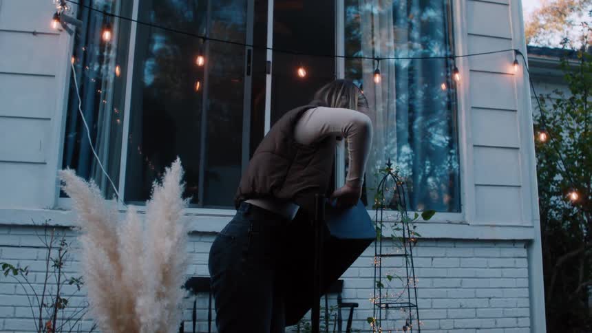 A woman setting up a speaker in her backyard