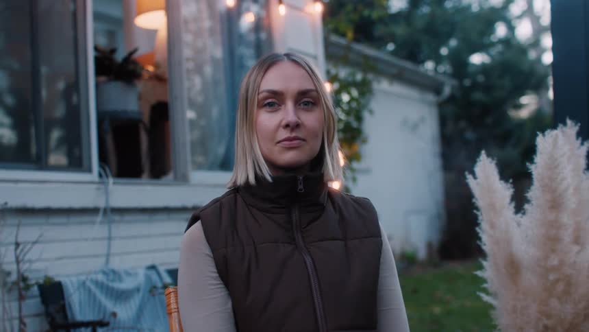 A sitting blonde woman is looking straight ahead