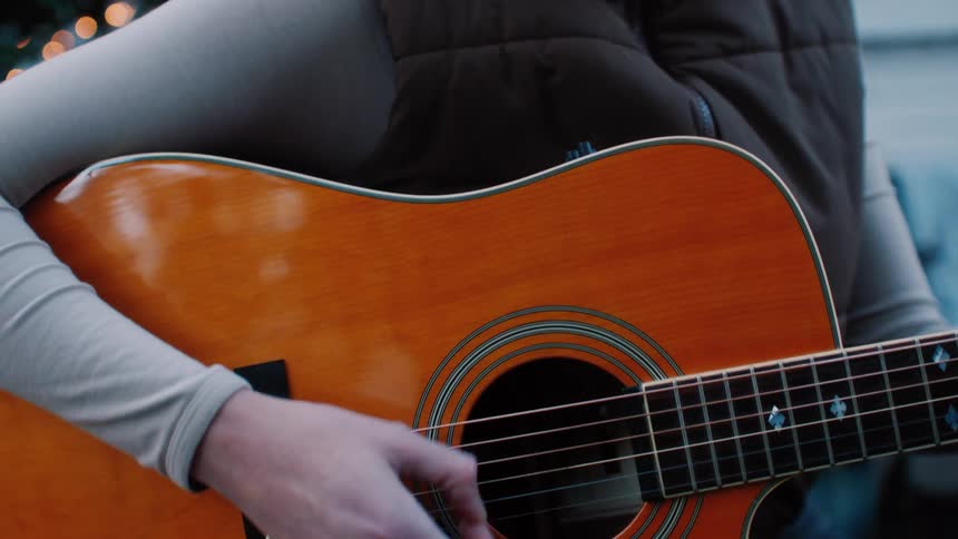 A woman singing and playing the guitar outdoors