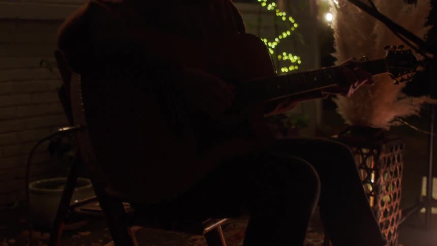 Singer singing and playing the guitar in an outdoor setting at night