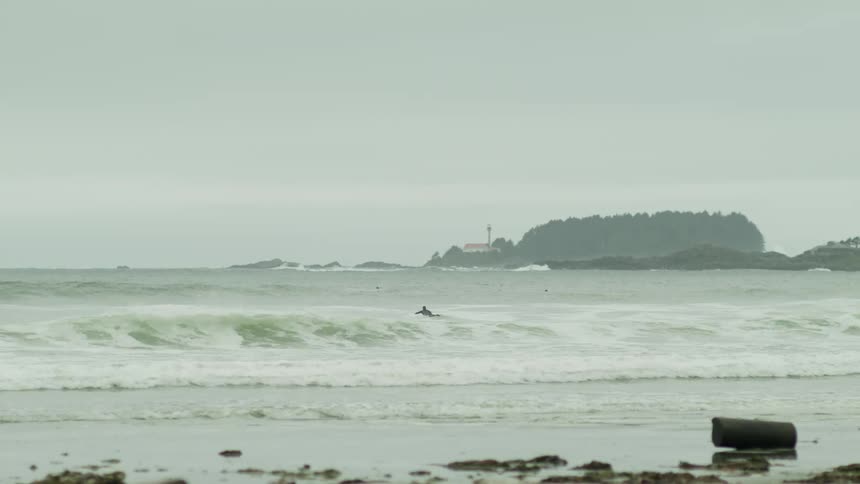 Surfers surfing in a sea with furious waves during the cloudy day