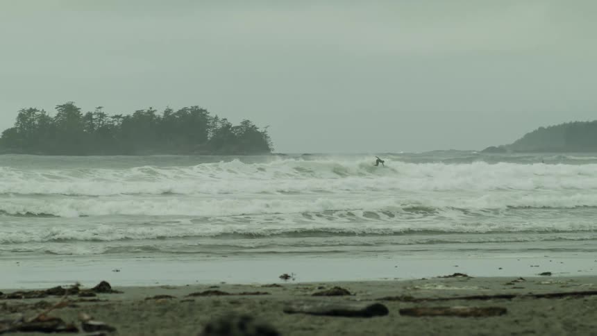 Surfer surfs between islands and beach on a foggy day