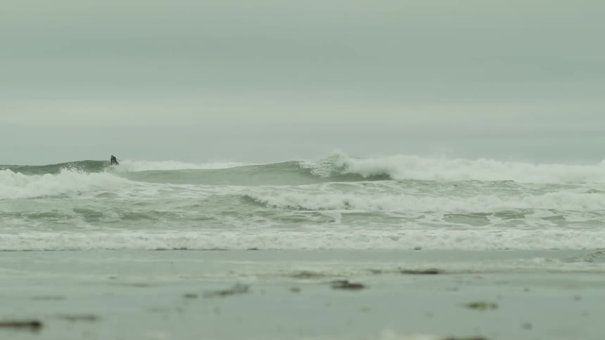 Two surfers riding waves on a very overcast day