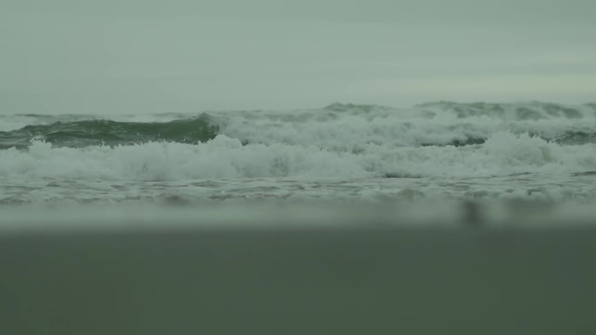 Waves hitting the shore of the beach on a cloudy day