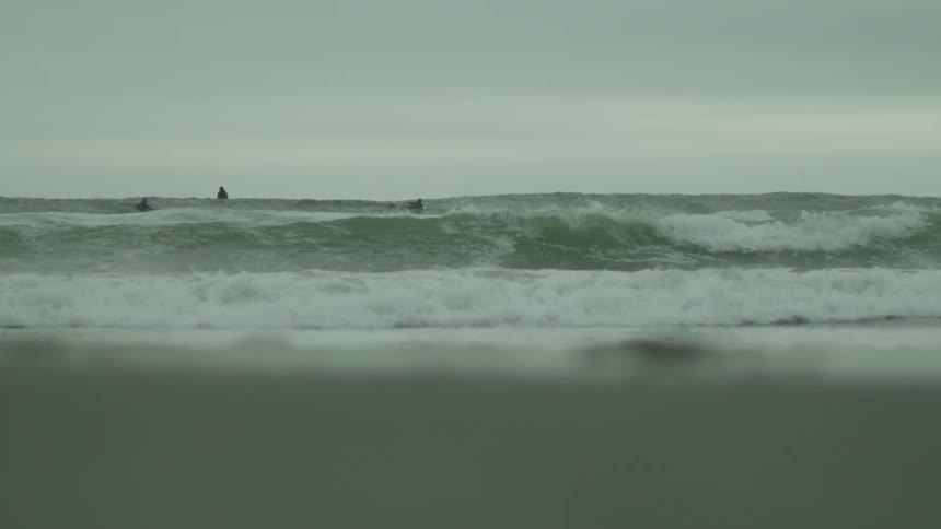 Two people are surfing near the shore
