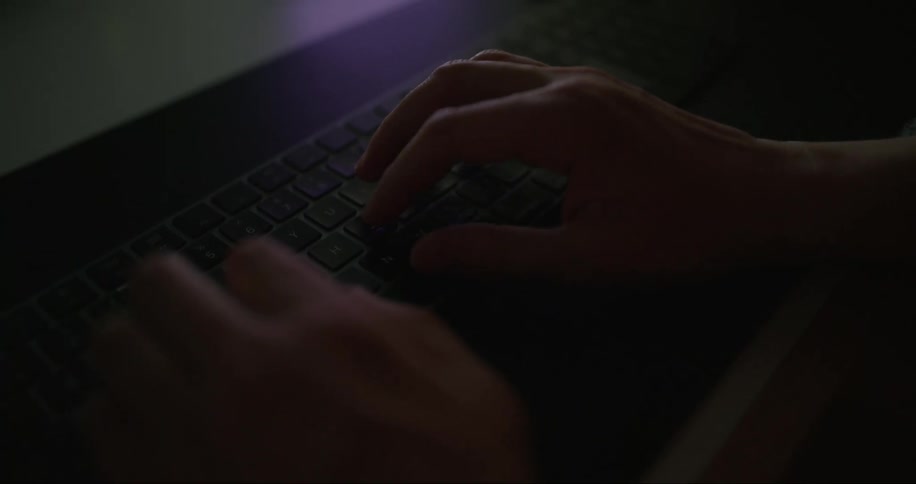 A mans hands typing on a wireless keyboard on a desk
