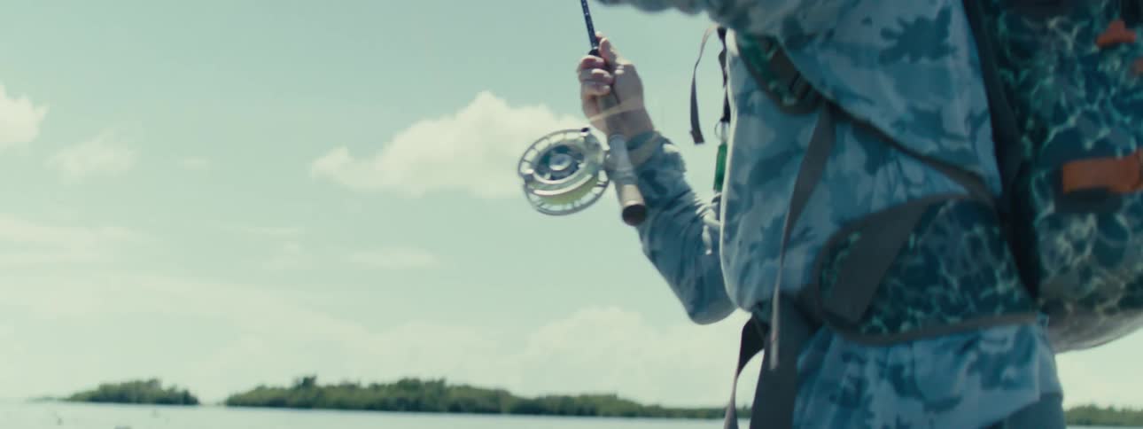 Man in a jacket fishing in shallow waters at sea