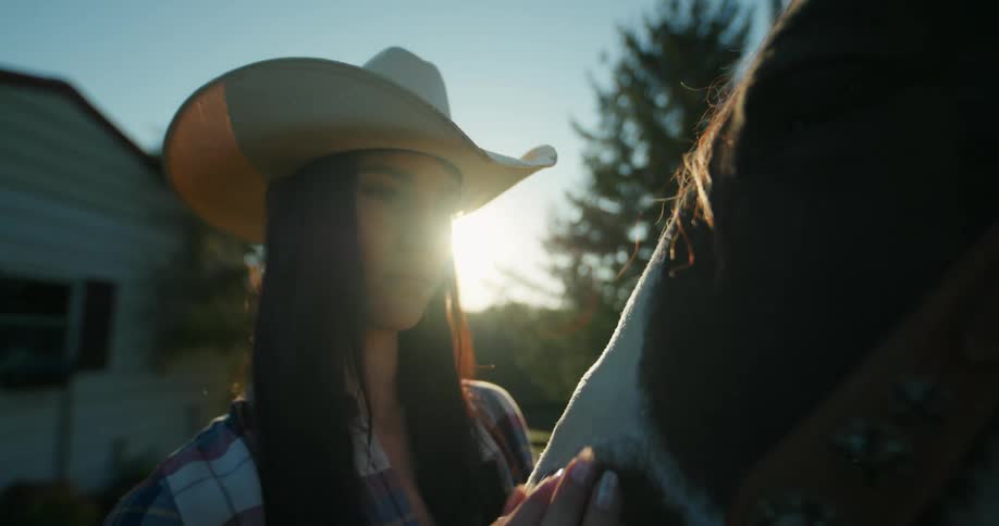 Young lady kisses the head of a horse while standing outdoor during the day