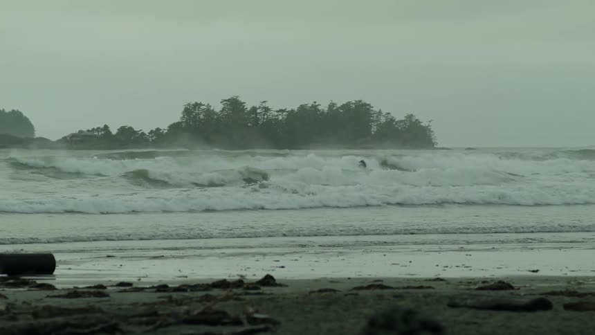 Person surfing in a rough sea with a cloudy landscape