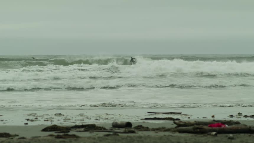 People surfing on the waves of the beach on a cloudy day
