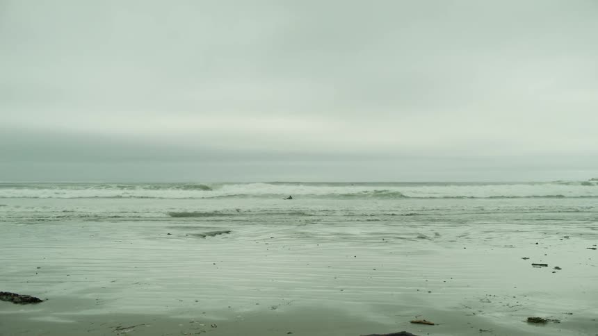 A beach with several small waves breaking at the seashore