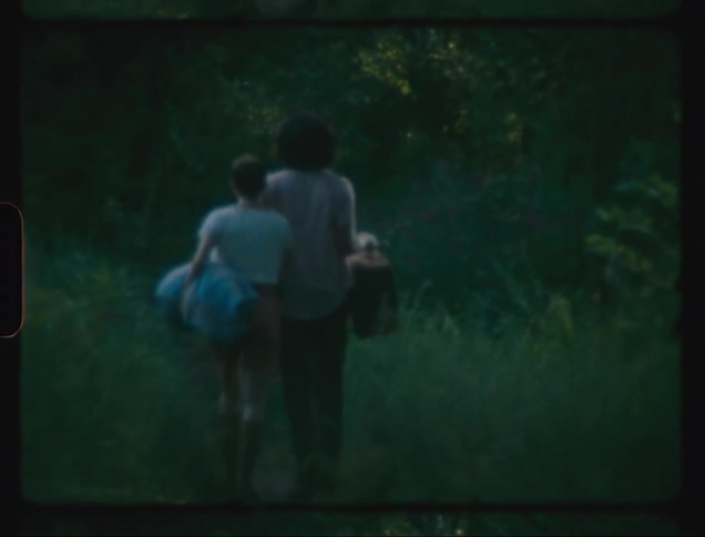 A couple walking hand in hand on a path with vegetation on their sides