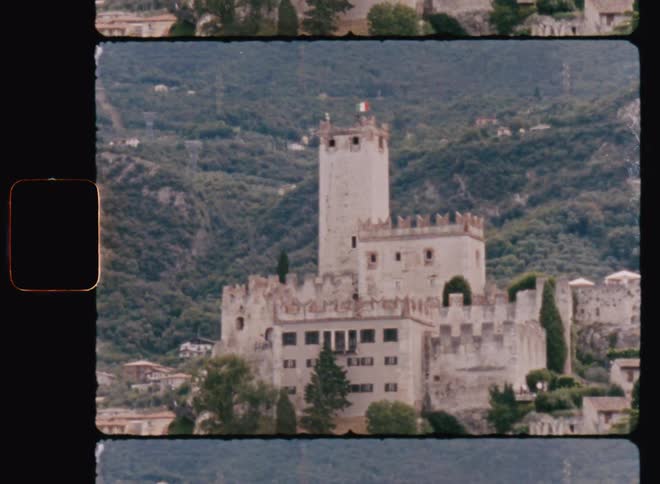 A castle stands in front of treecovered mountains