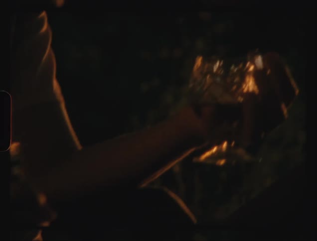 Man pours liquor and couple toasts while sitting outdoors