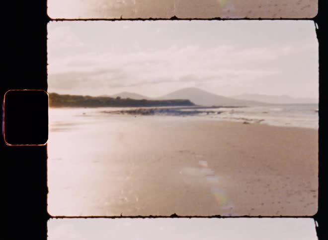 A sandy beach stretching along the ocean bathed in the warm hues of a sunset