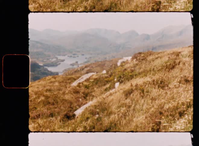 Hill overlooks water surrounded by hills and covered by dense fog