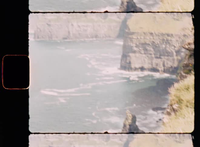 Waves crash against base of seaside cliffs on foggy day