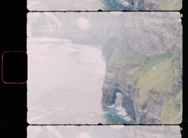 Grassy oceanside cliffs receive the foamy waves of the ocean