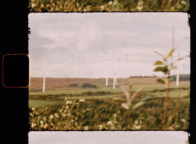 A rural field with wind farms during the day