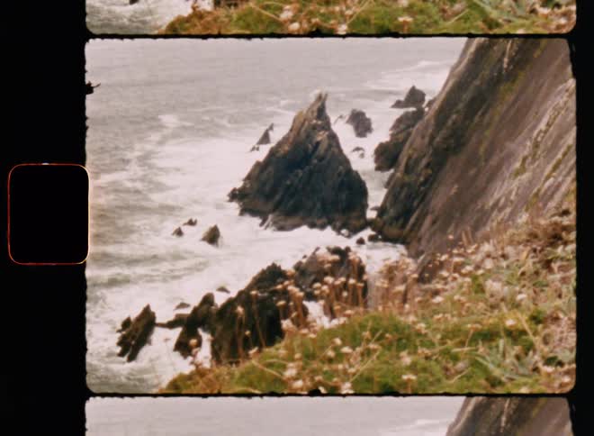 The waves crash on the rocks at the bottom of the cliff