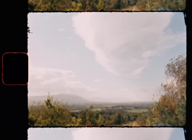 Archival of a windy day on a hill side with a large white cloud that tapers down in a bright sky during the day