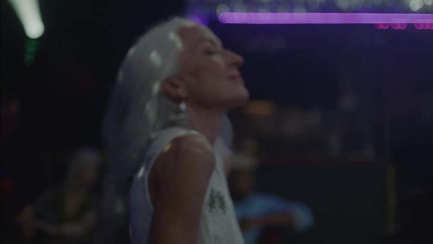 Older woman dancing in place in a club while she listens to a band