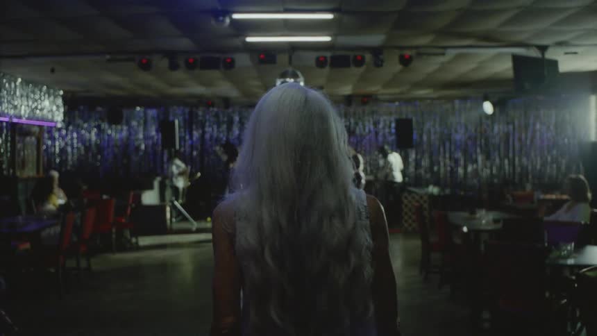 A lady walking through a night bar