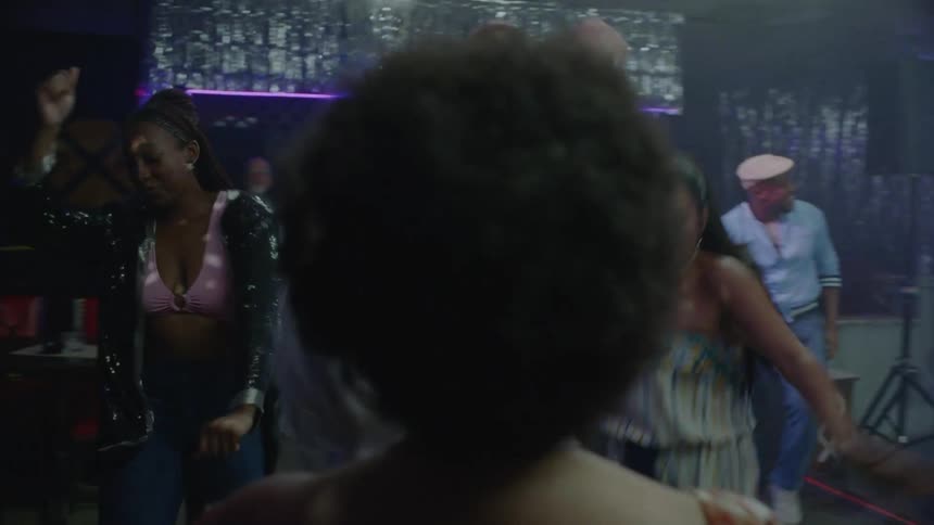 Grayhaired woman dancing freely in the middle of the dance floor at a nightclub surrounded by other people dancing and having fun