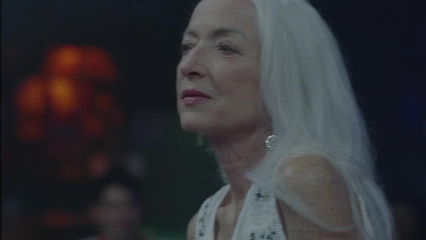 Woman with gray hair dancing in a nightclub and having fun
