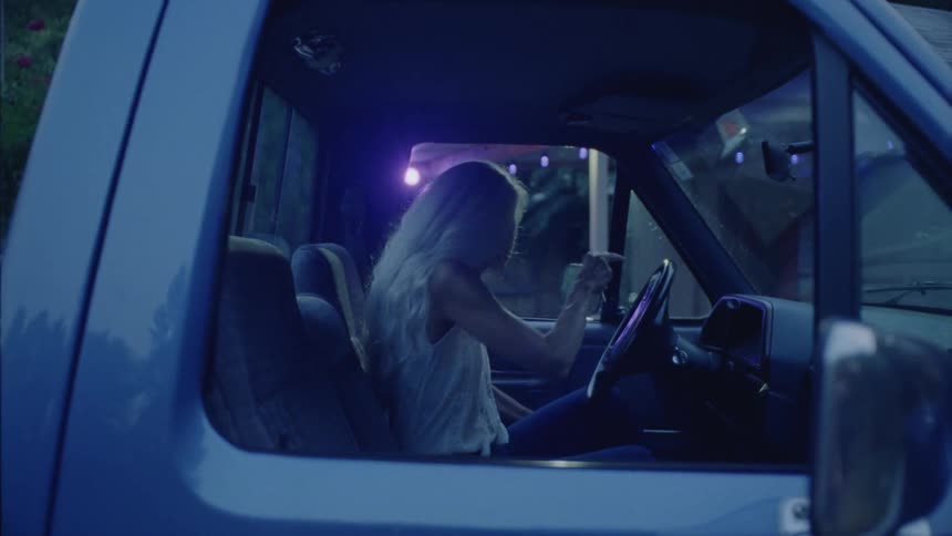 Woman inside the car turning off the engine looking at herself in the rearview mirror and getting out