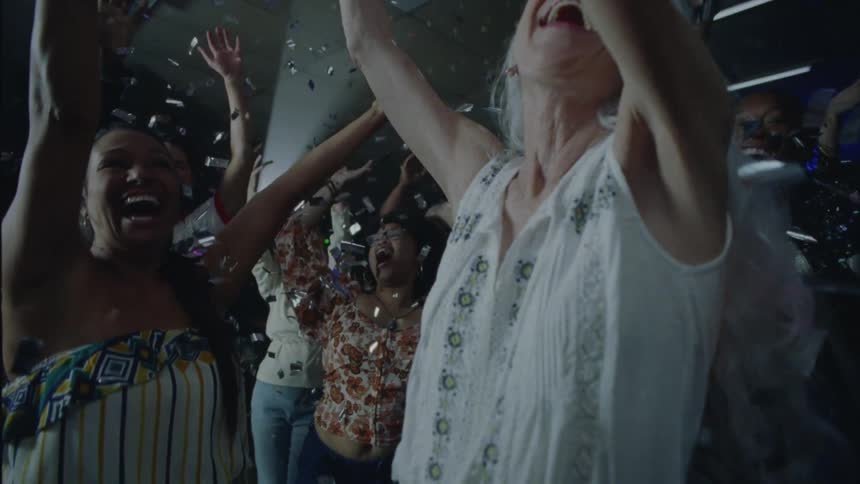 Silver confetti falls over crowd dancing under mirror ball