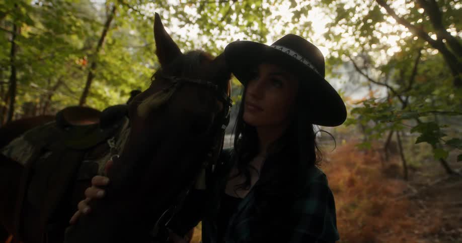 A woman is petting her horse in the woods