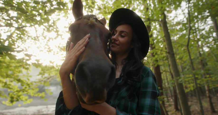 Woman caressing her horses face amidst a forest